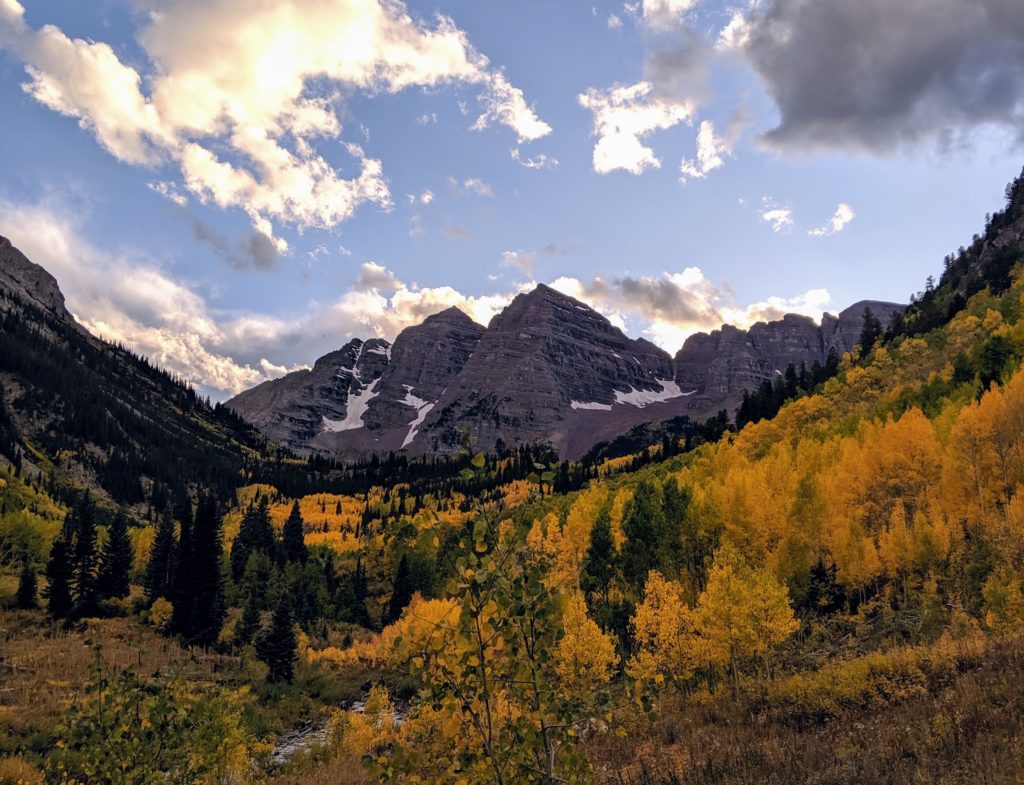 Maroon Peaks in Aspen Colorado in Autumn with yellow and green trees.