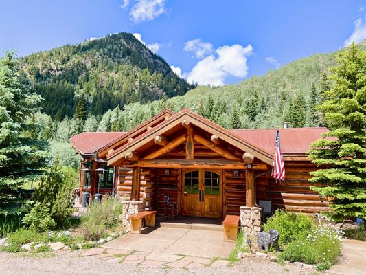 The Pine Creek Cookhouse cabin during the summer with a USA flag flying