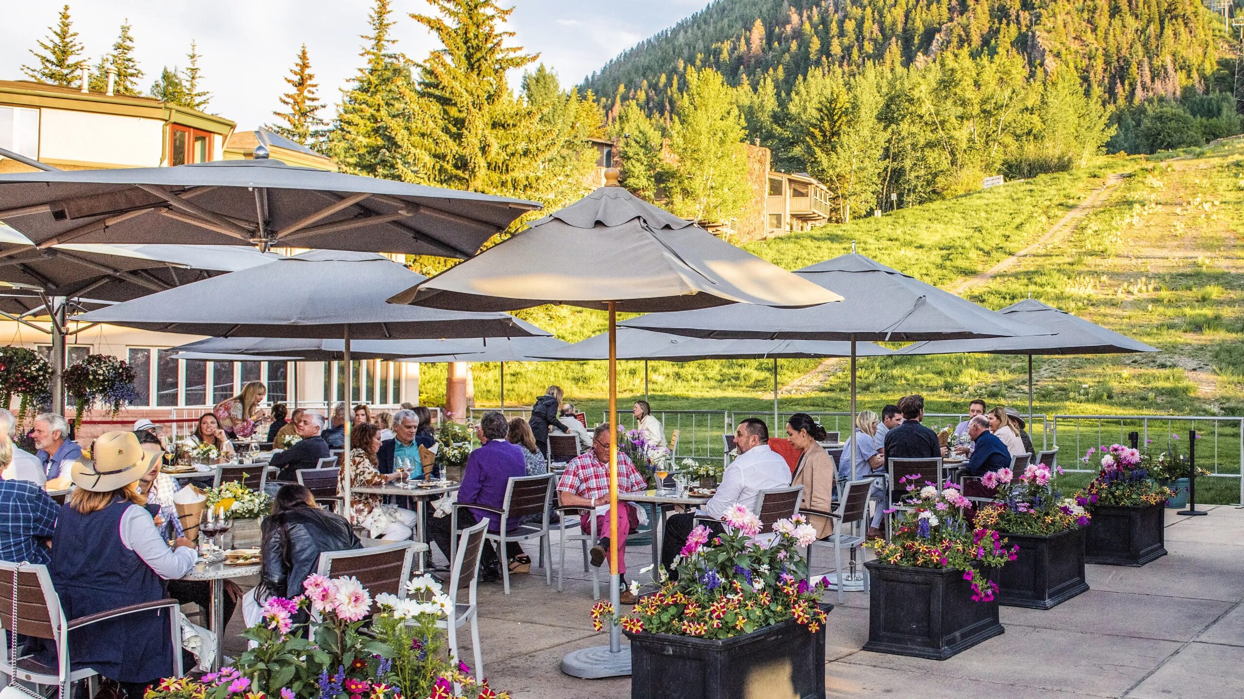 An outdoor patio with sun umbrellas at the base of Aspen Mountain