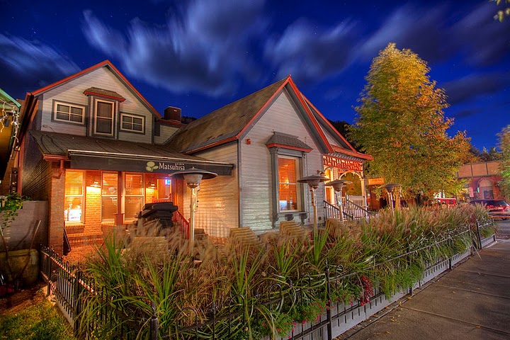 A villa light up at dusk with greenery