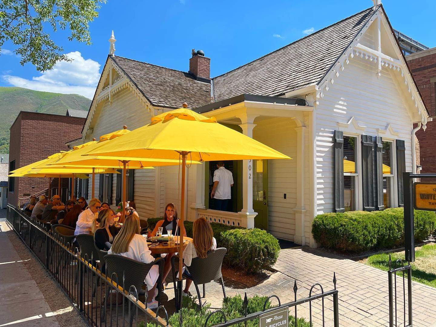 Yellow umbrellas on a patio outside a white cottage restaurant