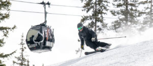 Skier enjoying fresh groomed runs beneath the Aspen gondola — luxury vacation rentals in Aspen near ski-in/ski-out access.