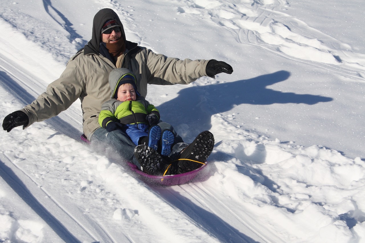 Father sledding down a snowy hill in Aspen with winter scenery