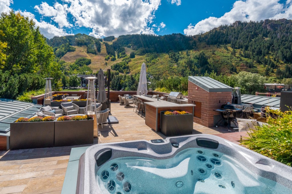 Luxury vacation rental home rooftop patio with a hot tub and outdoor lounge seating overlooking mountains in Aspen Colorado